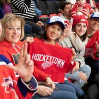 Alumni smile for a photo while watching the game at the Detroit Red Wings GVSU Night